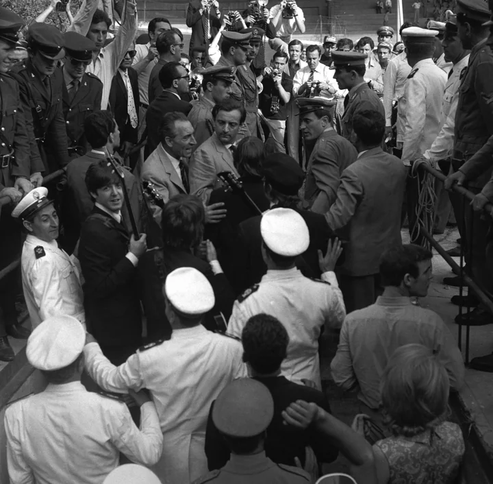 I Beatles circondati dai poliziotti prima di salire sul palco, Concerto dei Beatles al Velodromo Vigorelli, 24 giugno 1965. © Archivio Farabola